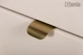 Zbliżenie na złoty uchwyt krawędziowy szafki Mia Smooth w kolorze macadamia mat